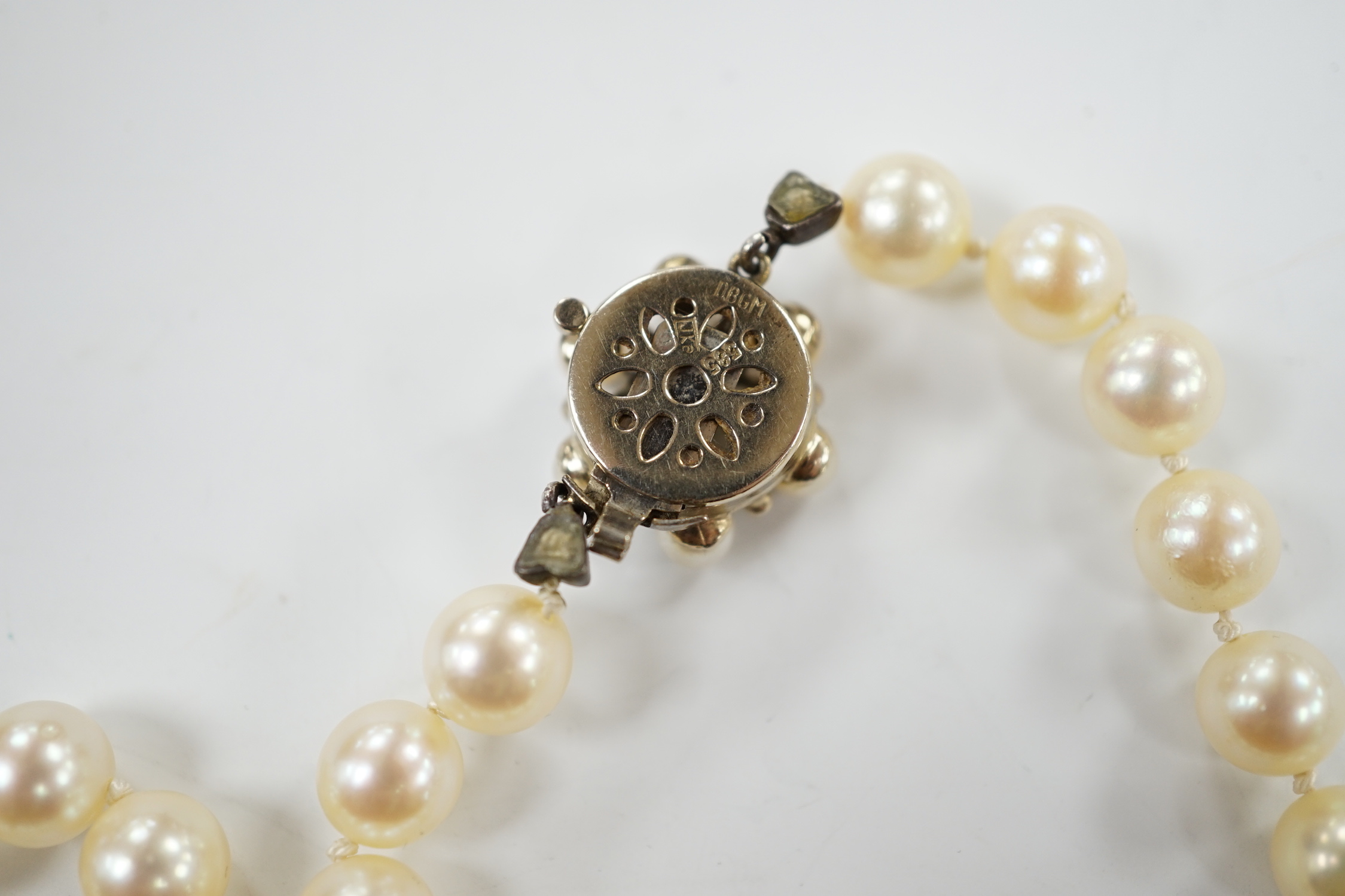 A single strand cultured pearl necklace, with cultured pearl and emerald set 585 yellow metal clasp, 49cm.
